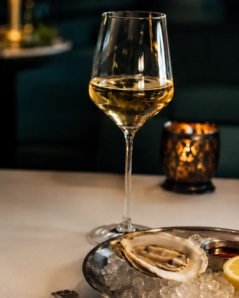 Glas Weißwein und frische Auster auf Eis im Nautilus